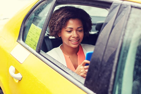 Happy African Woman Texing On Smartphone In Taxi